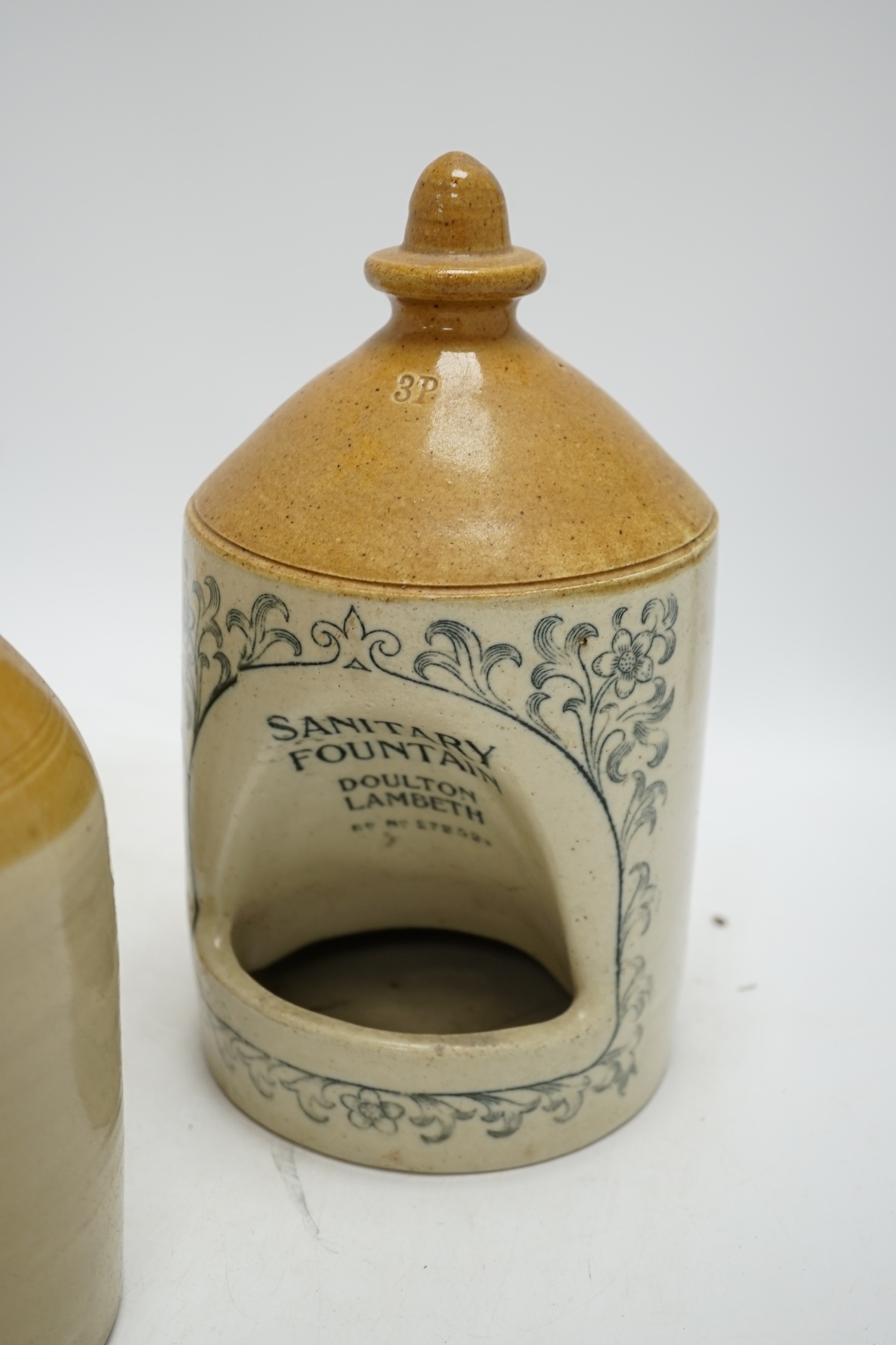 A late Victorian Doulton Lambeth Sanitary Fountain feeder, another similar, and a circular jar and cover, sanitary feeder 25cm high. Condition - sanitary feeder good, other feeder chipped and cover to jar chipped